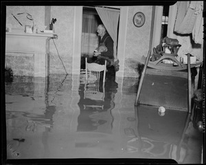 Man standing inside of a flooded house by window