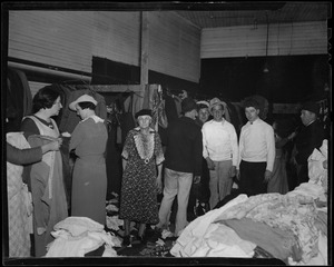 Group of men and women standing beside piles of clothes