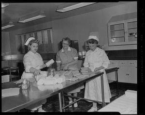 A woman and two nurses standing at a table with supplies
