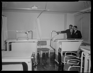 Reps. John F. Thompson and James L. O'Dea standing beside a hospital bed looking at a light