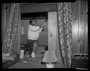 Woman using a hammer to board up a window in preparation for Hurricane Edna