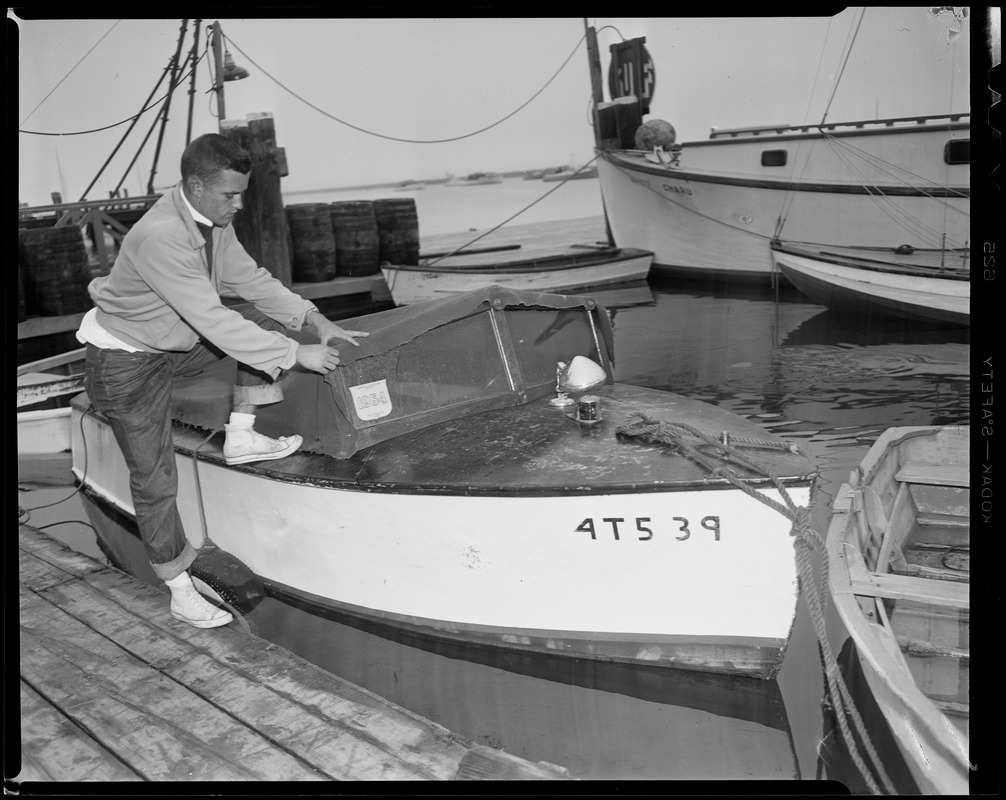 Man pulling tarp onto boat number 4T539 in preparation for Hurricane Edna