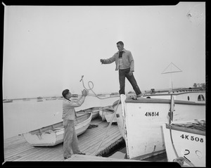 Man on boat number 4N814, throwing rope to another man on the dock, preparing for Hurricane Edna