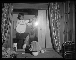Woman using a hammer to board up a window in preparation for Hurricane Edna