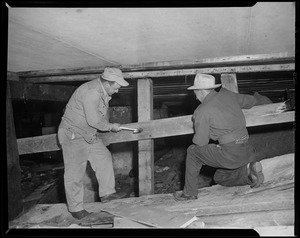 Two men installing plywood boards