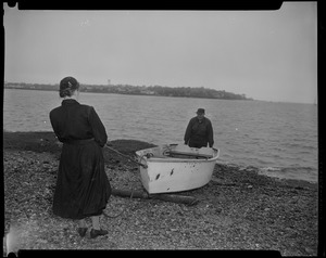 Man and woman pulling a row boat onto beach in preparation for Hurricane Edna