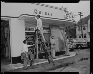 Four people boarding windows at Quincy gas station in preparation for Hurricane Edna