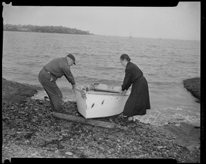 Man and woman pulling a row boat onto beach in preparation for Hurricane Edna