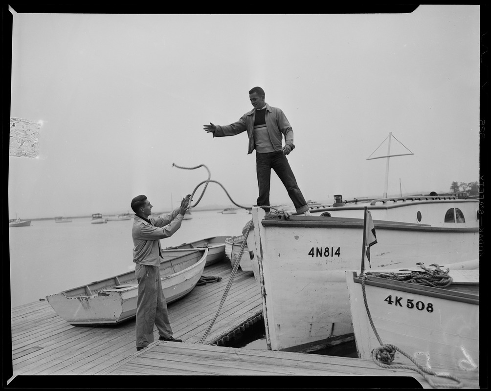 Man on boat number 4N814, throwing rope to another man on the dock,  preparing for Hurricane Edna - Digital Commonwealth