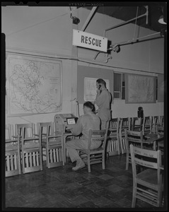 State Police Trainees, George Cassell, at teletype machine and John L. Lacasse, at telephone, advising rescue operations, in control room of Civilian Defense, Framingham