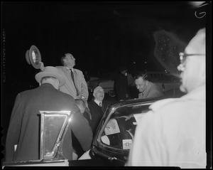 Adlai Stevenson waving his hat to the crowd next to a car