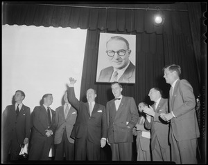 Adlai Stevenson on stage waving and addressing crowd with several others including his sons (far left) and John F. Kennedy (far right)