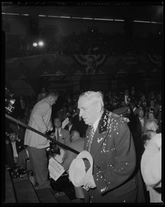 Man in overcoat, holding hat and covered in confetti