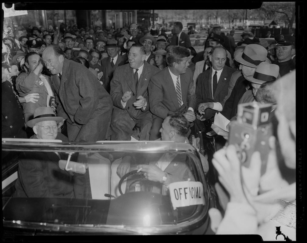 Adlai Stevenson in convertible with Foster Furcolo and John F. Kennedy, surrounded by a crowd