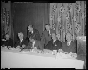 Edward McCormack, John F. Kennedy, Adlai Stevenson, Mayor John B. Hynes and one other seated at dinner table with Paul Dever and Foster Furcolo standing behind them