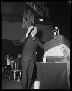 Man at podium, addressing crowd, indoors