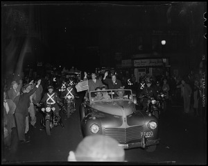 Adlai Stevenson and Paul Dever waving from car moving through parade with police escort