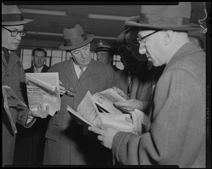 Adlai Stevenson looking at newspapers with group