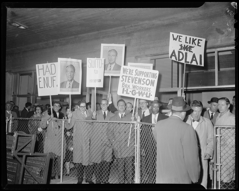 Group of people behind a fence holding up signs in support of Adlai Stevenson
