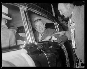 Adlai Stevenson sitting inside a car with a man standing outside of the car