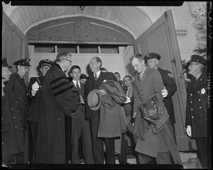 Adlai Stevenson shaking hands with a man in academic robe in a doorway