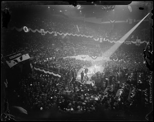 View of a stadium filled with people with a man standing on the podium in the center