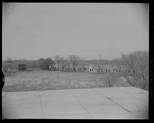 Exterior view of Fort Warren behind a row of trees with a house next to it
