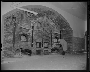 Man looking at ovens in wall at Fort Warren