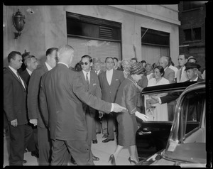 King Bhumibol Adulyadej and Queen Sirikit of Thailand entering car, surrounded by men