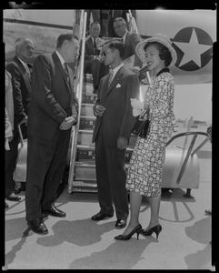 King Bhumibol Adulyadej and Queen Sirikit of Thailand at bottom of airplane steps speaking to Governor Foster Furcolo