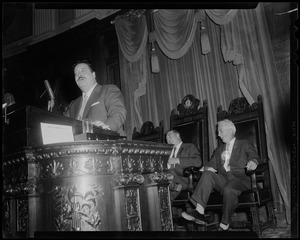 Filmstage-television comedian Jackie Gleason stands at a speaker's podium as he addressed the House of Representatives at the State House