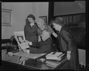 A man and three women looking at copy of the Record American Glenn Orbit Picture Book