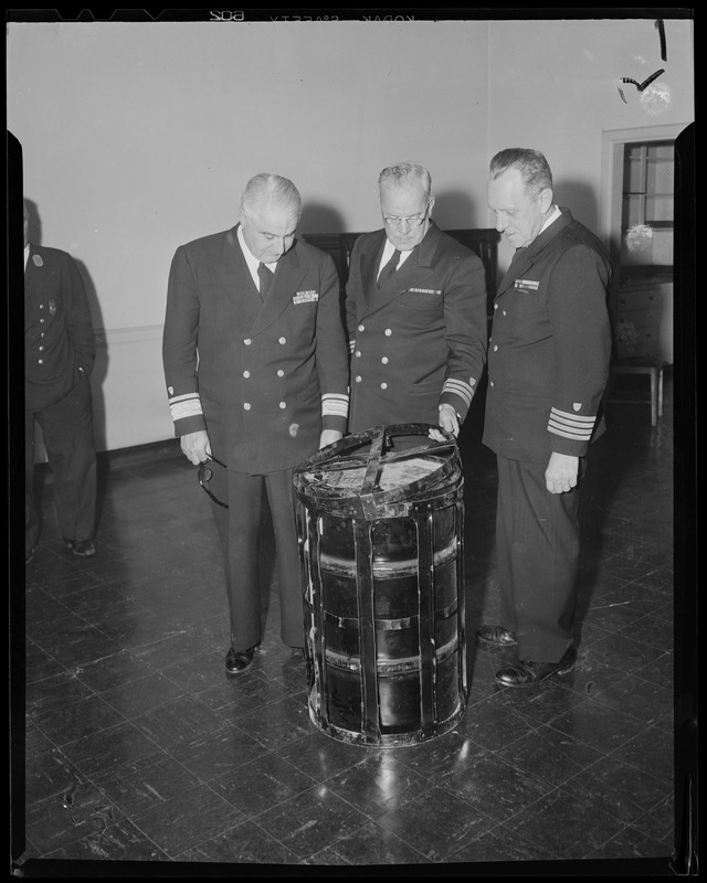 Three military men inspecting a barrel