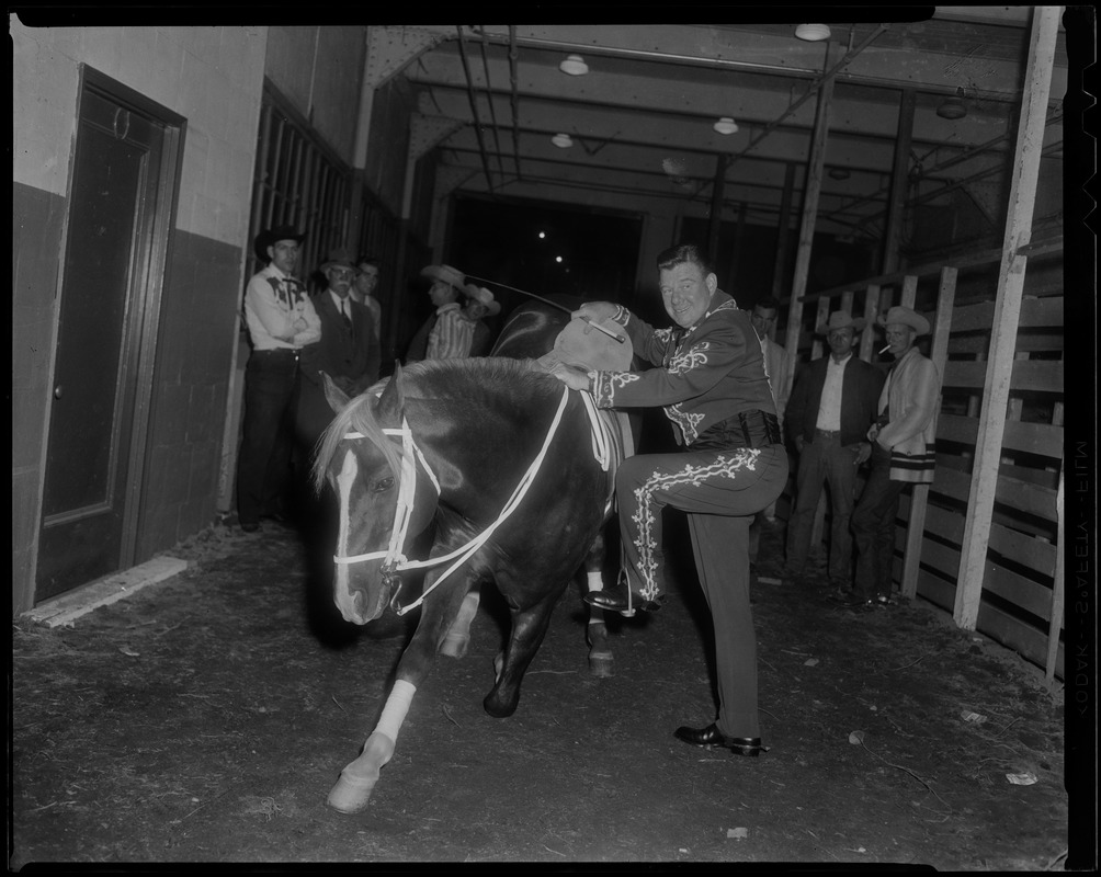Arthur Godfrey mounting his horse "Goldie" to join the Rodeo at the Boston Garden