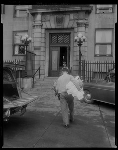 Deliveryman walking toward building entrance with boxes and flowers