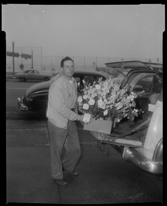 Deliveryman unloading floral arrangement from station wagon