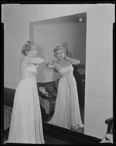 Eva Gabor fluffing her hair, looking into mirror