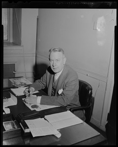 James W. Austin seated at desk, holding a writing utensil