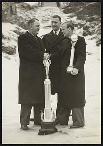 Sigmund Ruud winner of the National and Eastern Ski Jump Championship Meets of 1937 receiving from Captain Edward L. Lydiard, Director, the trophy for high point score of last year's meet. l.r. Captain Edward L. Lydiard, Director, Eastern Ski Championship, Harold Nelson, President, Norway Ski Club of New York, Chief of Tournament Sigmund Ruud, Norway's congenial ambassador of good will. In the combination of silver and bronze and the first leg was won by Sigmund Ruud for a championship jump of last year. In order to retain permanently this beautiful trophy a skier must win three legs. This year the battle is on to retain permanently in this country the possession of a trophy according to Sigmund Ruud, whom we now quote; This trophy is the most beautiful prize that have ever seen offered to a skier for his efforts in any part of the world."