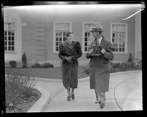 A woman walking next to a man holding a camera
