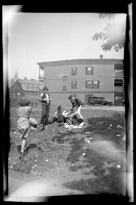 A woman holding a hat walks toward a group sitting outside