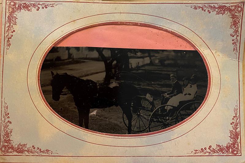 Three young people in a cart being pulled by a horse