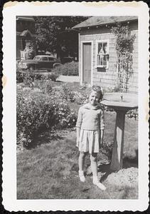 A young girl seen standing by a birdbath in the backyard of 27 Pleasant Street