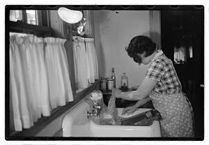 A woman doing laundry at a sink with a washboard