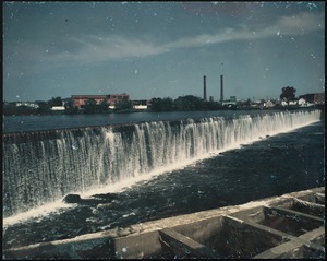 Water flowing over a dam with cityscape