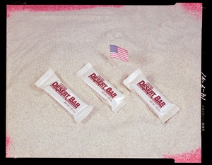 Food lab, desert shield, candy bar on sand with flag