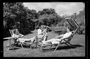 Three women outside on chaises lounges