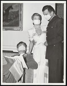 Film Stars Combat Influenza Because of the large number of people in Los Angeles and Hollywood afflicted with influenza, the 20th Century Fox Studio is taking all precautions to protect their start working in pictures. ---- Photo Shows---- Left to right -- Henry Wilcoxen, Nancy Kelly, John Loder, are shown wearing respiratory "flu masks" as they study film script on set today.