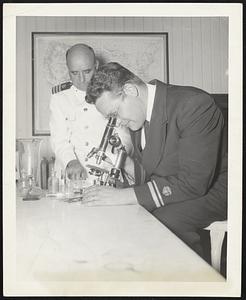 Laboratory Examination -- Specimens from a suspected vessel are examined under the microscope by Acting Assistent Surgeon Kudish, while Senior Surgeon James E. Faris prepares the specimens for inspection.