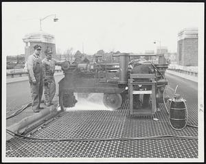 Exclusive "Manicurist"-This $30,000 milling machine - the only one of its kind in the world-shown trimming and filing the steel deck grid surface of the Cottage Farm overpass to increase to coefficient of friction and make the roadway safer for motorists. Left to right, Engineer Clyde Parson and his assistant, Joseph Sciarra, watch while Joseph Veitz applies just the right pressure for the steel manicure.